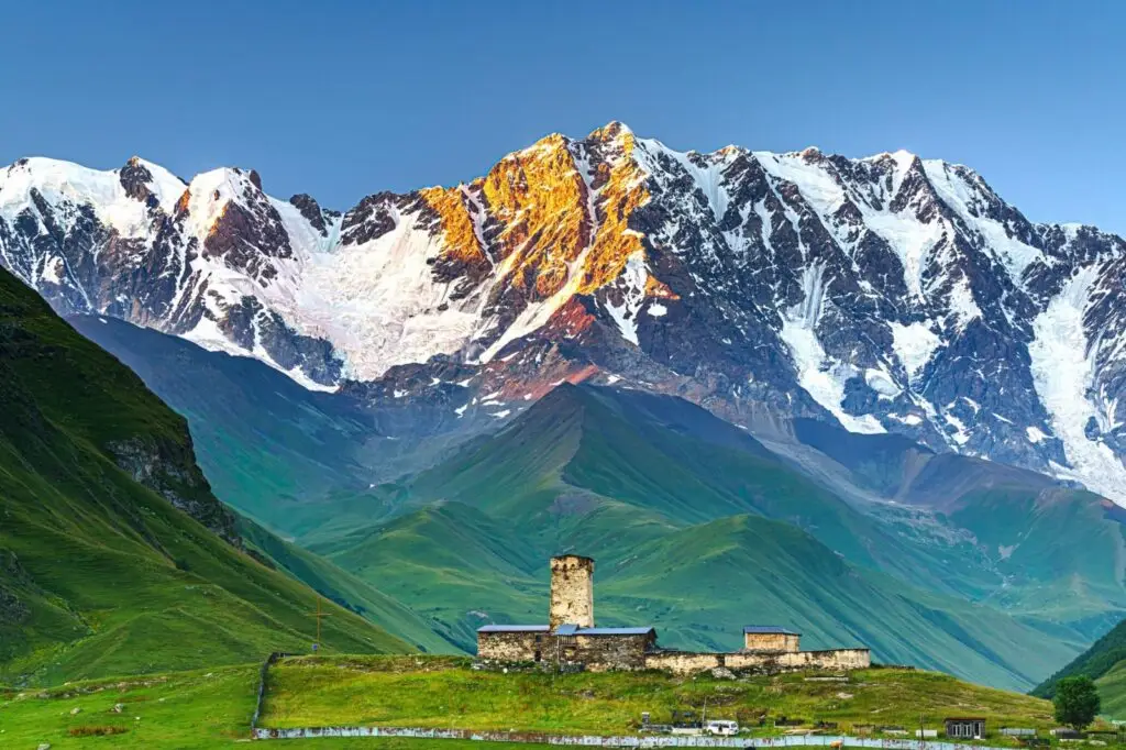 A stunning view of the snowy Caucasus Mountains and green valleys, a top destination for nature lovers who visit Georgia for adventure tourism in Georgia